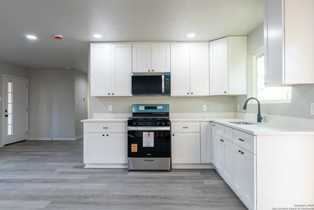 a kitchen with stainless steel appliances a stove top oven a sink a window and cabinets