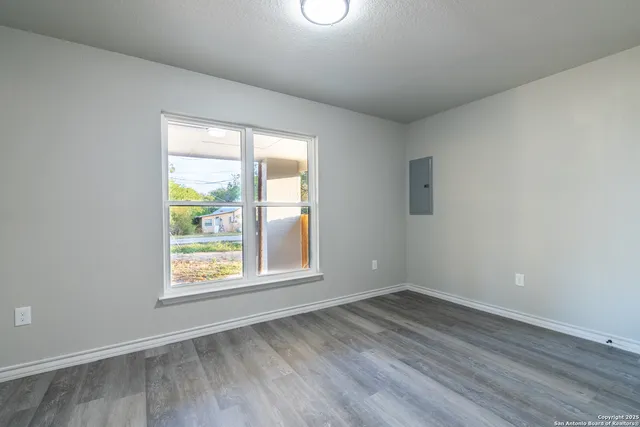 an empty room with wooden floor and windows