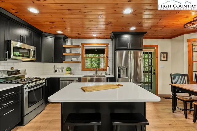 a kitchen with a stove a sink dishwasher a refrigerator with wooden cabinets and floor