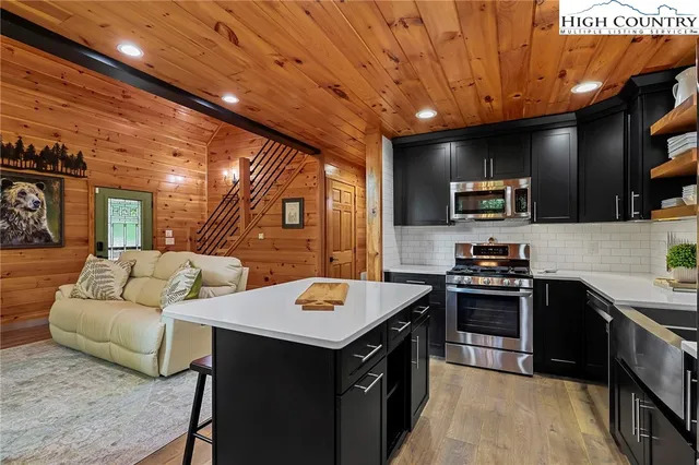 a kitchen with a stove a sink dishwasher a oven with a dining table and chairs with wooden floor