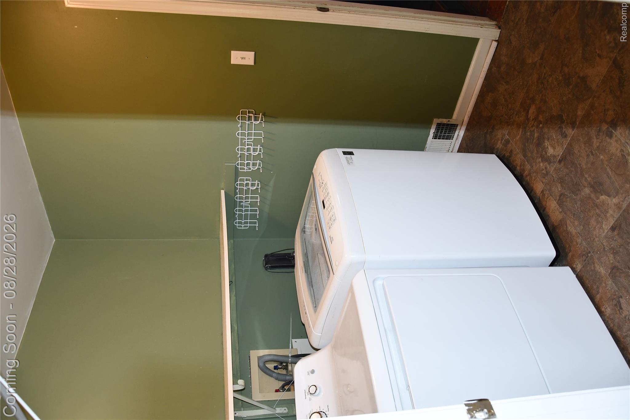 9039 Peer Road South Lyon, MI 48178 - Photo 23 of 47 Laundry area featuring a utility shelf, wall-mounted drying rack, and durable flooring