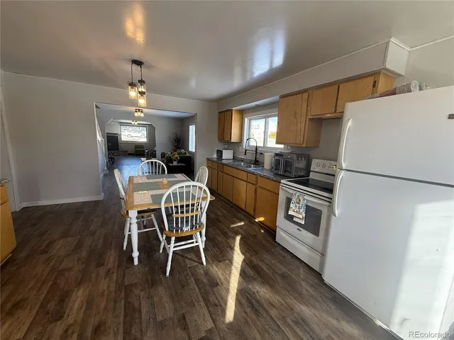 a kitchen with stainless steel appliances a dining table chairs refrigerator and sink