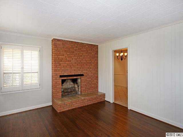 7945 Woodleaf Road Woodleaf, NC 27054 - Photo 4 of 16 an empty room with wooden floor fireplace and windows