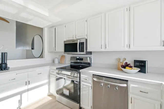 a kitchen with white cabinets and a stove with wooden floor