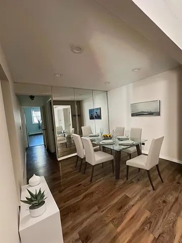 a living room with couches and a dining table with wooden floor