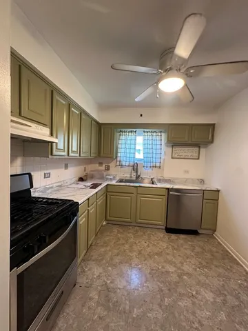 a kitchen with stainless steel appliances kitchen island granite countertop a stove and cabinets