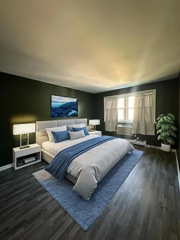 a spacious bedroom with a bed a dresser and wooden floor