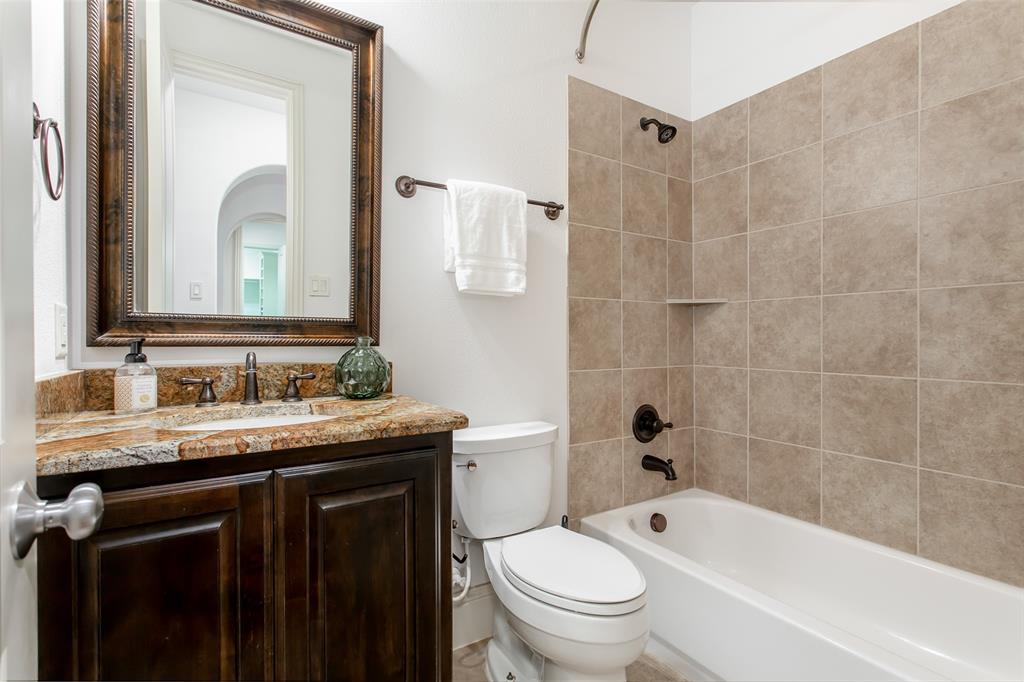 846 Deerfield Road Allen, TX 75013 - Photo 26 of 40 Bathroom featuring a built-in vanity with a stone countertop, an integrated sink, a framed mirror, and a bathtub with a tiled surround