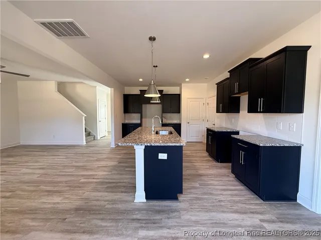 a kitchen with stainless steel appliances kitchen island granite countertop a stove top oven a sink dishwasher and a microwave oven on the blue kitchen countertops