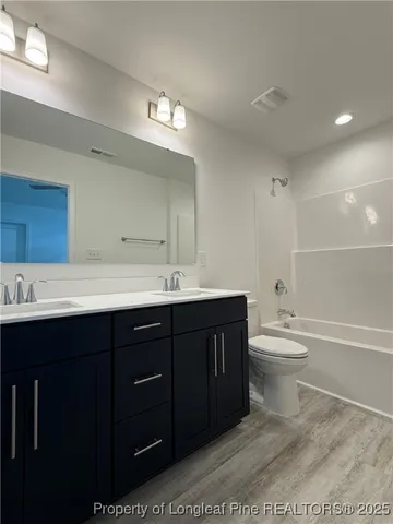 a bathroom with a double vanity sink a toilet and a bathtub