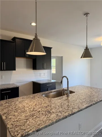 a kitchen with kitchen island granite countertop a sink a counter top space and cabinets