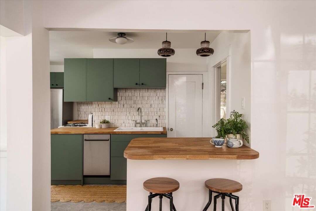 6036 Eucalyptus Lane Los Angeles, CA 90042 - Photo 11 of 34 a kitchen with stainless steel appliances a table and chairs in it