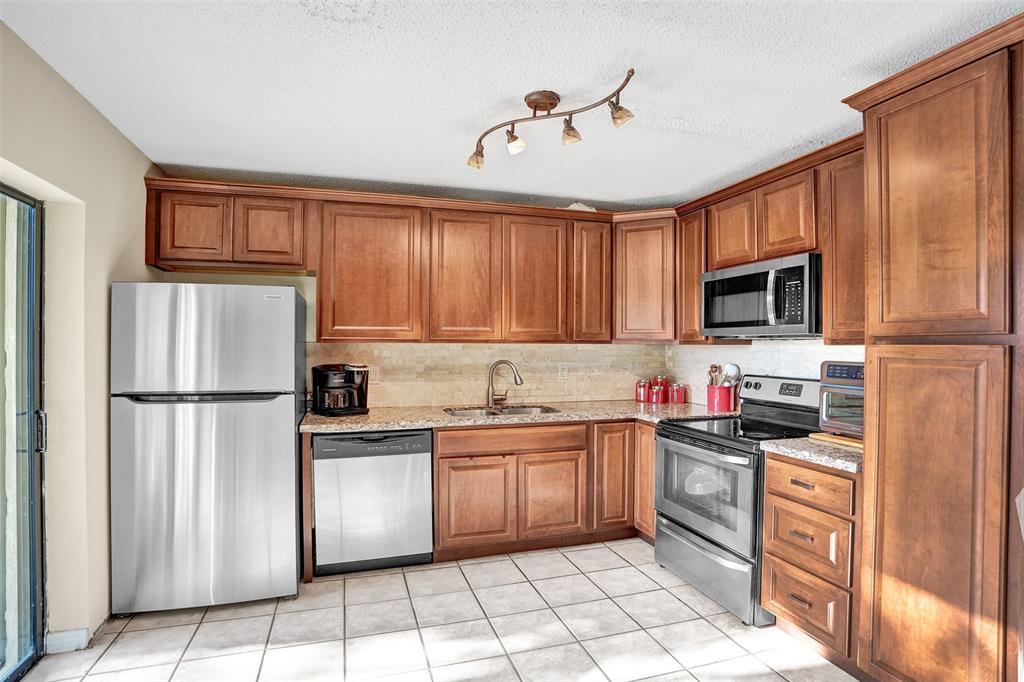 1525 Augusta Circle, Unit 109 Delray Beach, FL 33445 - Photo 7 of 23 a kitchen with granite countertop a refrigerator stove top oven and sink