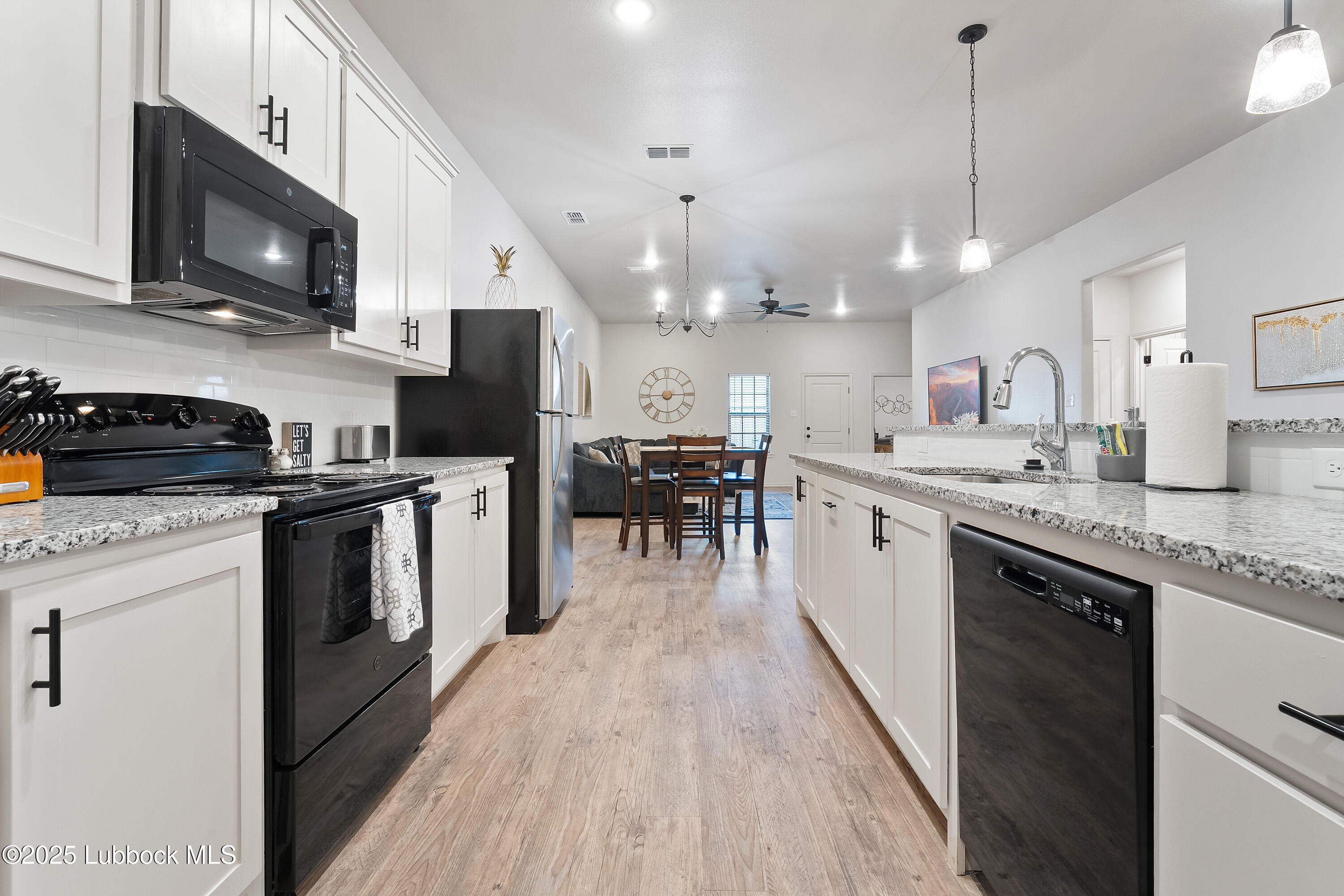 5528 Lehigh Street Lubbock, TX 79416 - Photo 13 of 23 a kitchen with stainless steel appliances granite countertop a refrigerator a stove top oven a sink dishwasher and white cabinets with wooden floor
