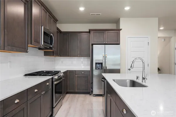 a kitchen with stainless steel appliances granite countertop a sink stove and refrigerator