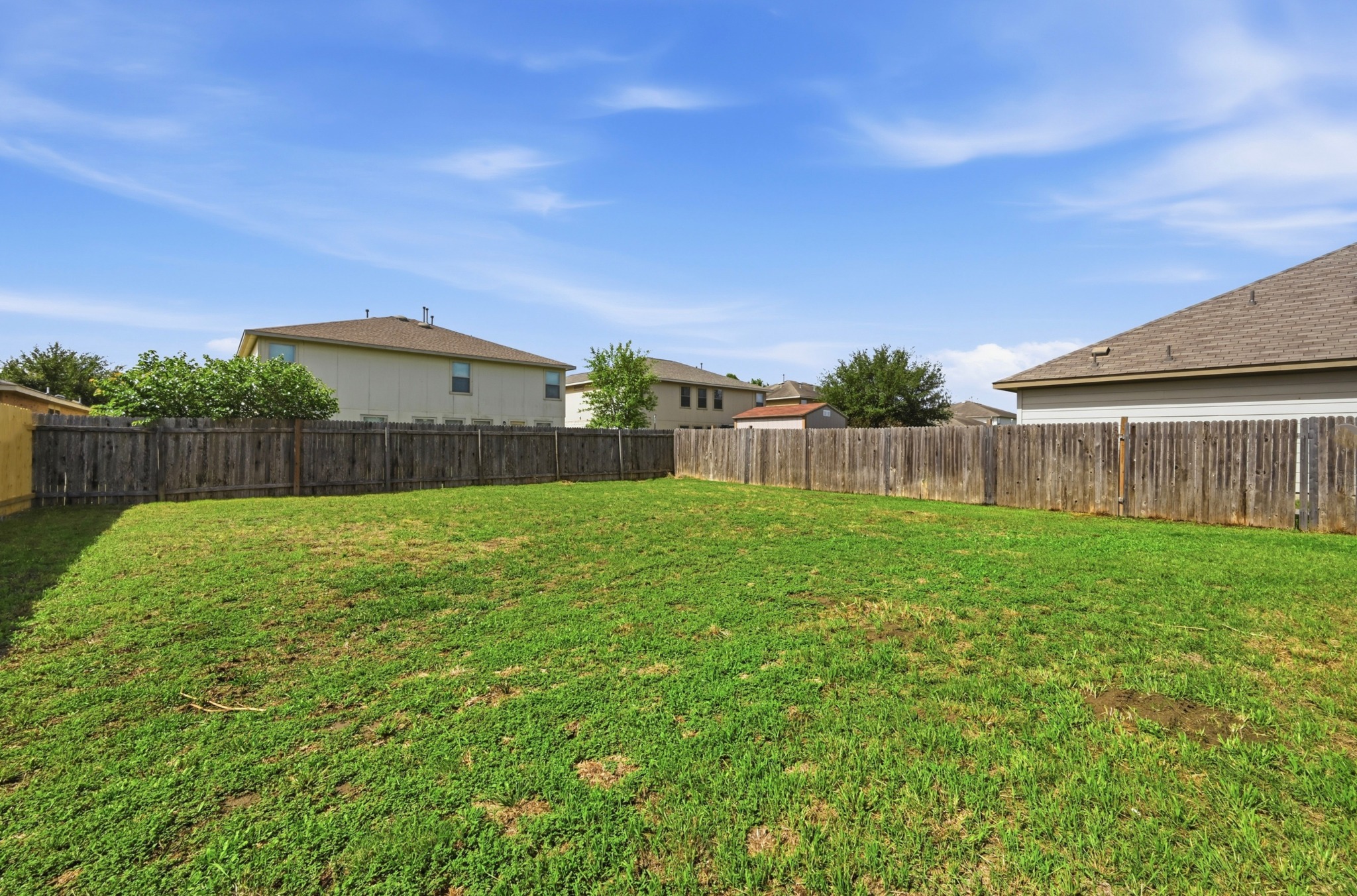 209 Noddy Road Buda, TX 78610 - Photo 25 of 30 Expansive backyard featuring a manicured lawn and complete wood privacy fencing