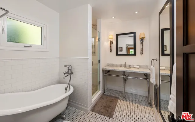 a bathroom with a tub a sink and a mirror