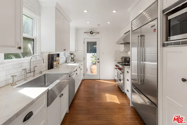 a large kitchen with stainless steel appliances kitchen island granite countertop a refrigerator and a sink