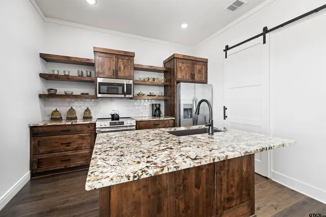 a view of kitchen island with stainless steel appliances granite countertop a stove and a sink