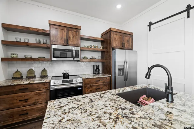 a kitchen with stainless steel appliances kitchen island a refrigerator sink and cabinets