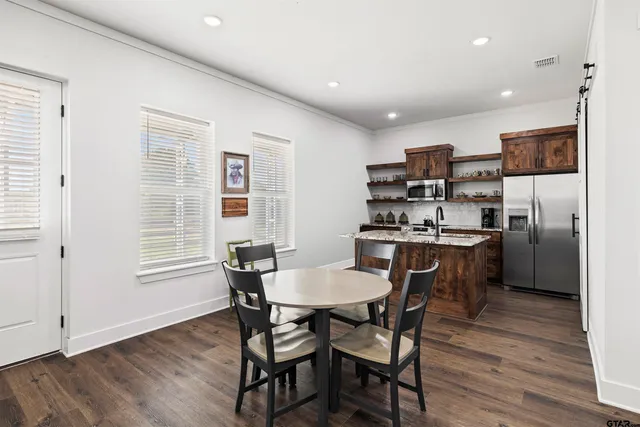 a kitchen with stainless steel appliances a dining table chairs and wooden floor