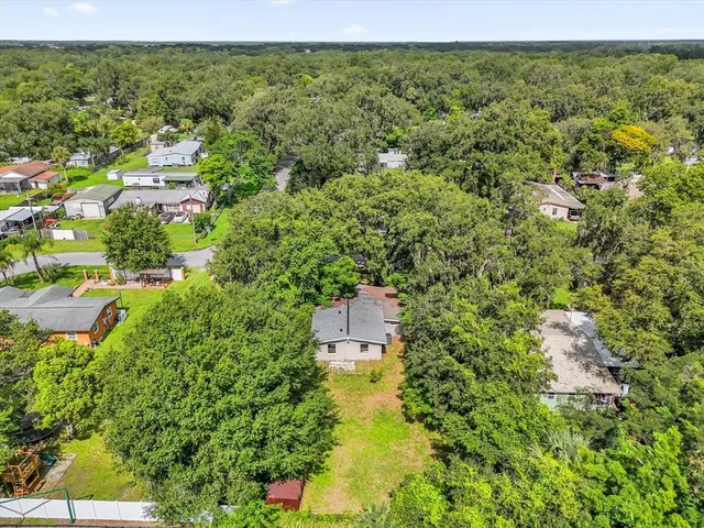 an aerial view of residential house with outdoor space and trees all around