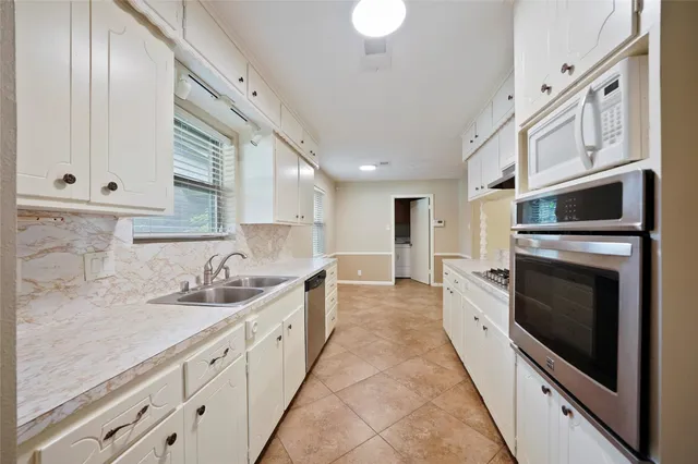 a large white kitchen with a stove a sink a microwave and a refrigerator