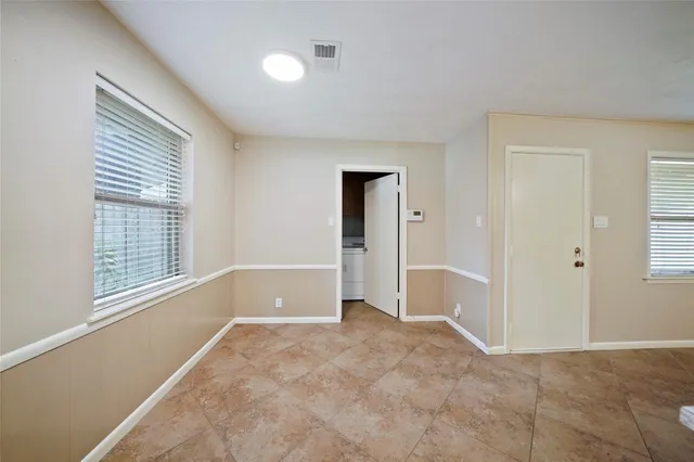 a view of an empty room with wooden floor and a ceiling fan