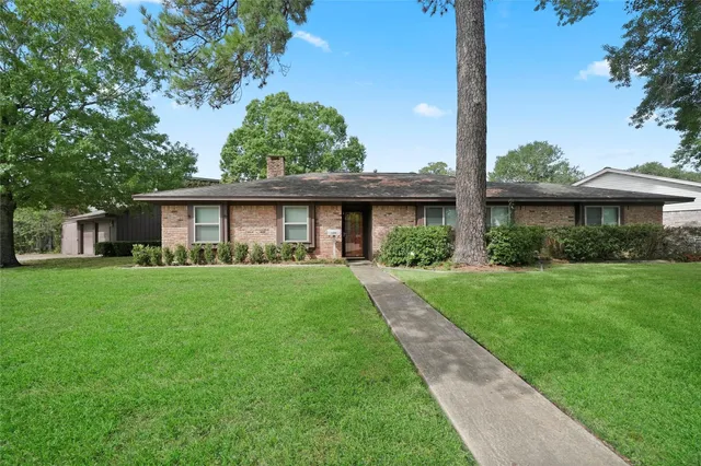 a view of a house next to a yard with big trees