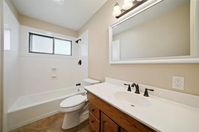 a backyard of a house with plants and a large tree