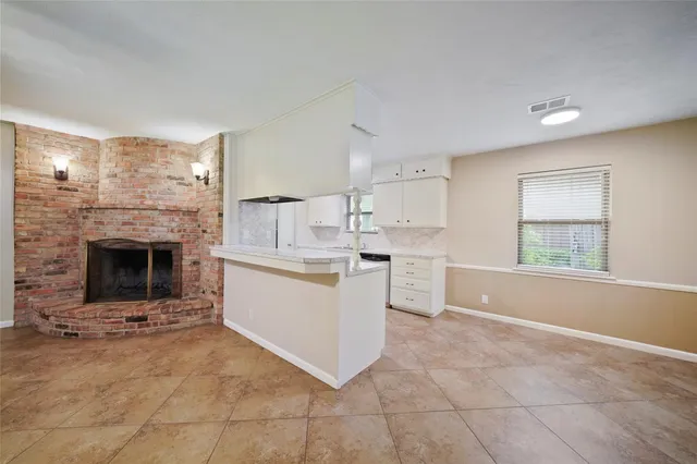 an empty room with windows and fireplace