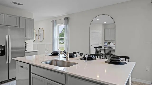 a kitchen with sink a refrigerator and chairs