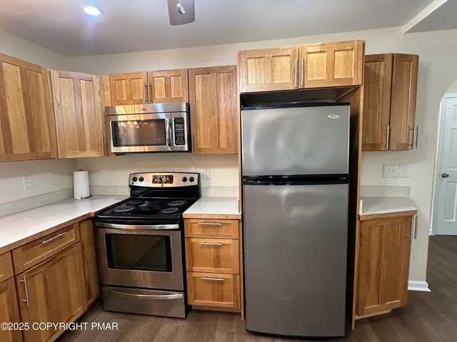 a view of kitchen with kitchen island a dining table chairs stainless steel appliances and cabinets