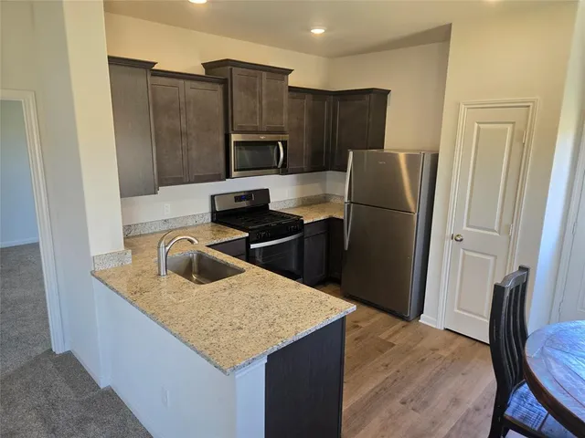 a kitchen with kitchen island a refrigerator stove a sink and dishwasher with wooden floor