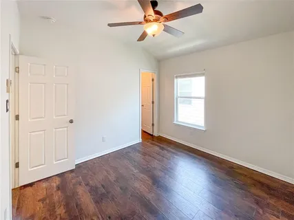 an empty room with wooden floor chandelier fan and windows