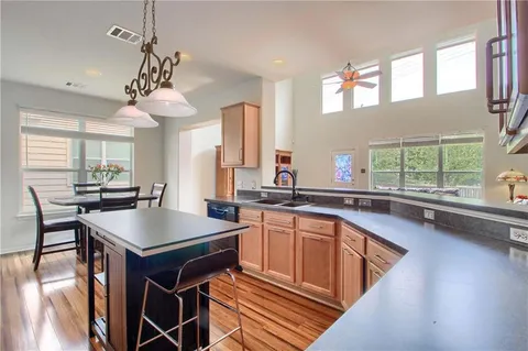 a kitchen with a stove a sink dishwasher a dining table and chairs with wooden floor
