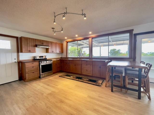 81-1010 St John's Road Kealakekua, HI 96750 - Photo 8 of 30 a kitchen with stainless steel appliances granite countertop a stove top oven a sink dishwasher a dining table and chairs with wooden floor