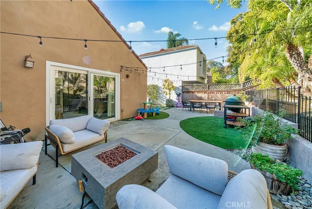 a view of a patio with couches table and chairs with plants and wooden fence