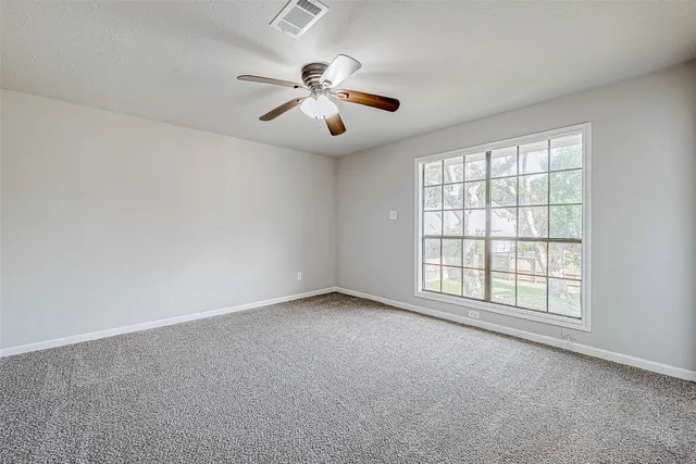 an empty room with windows and fan