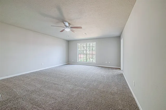 an empty room with windows and ceiling fan view