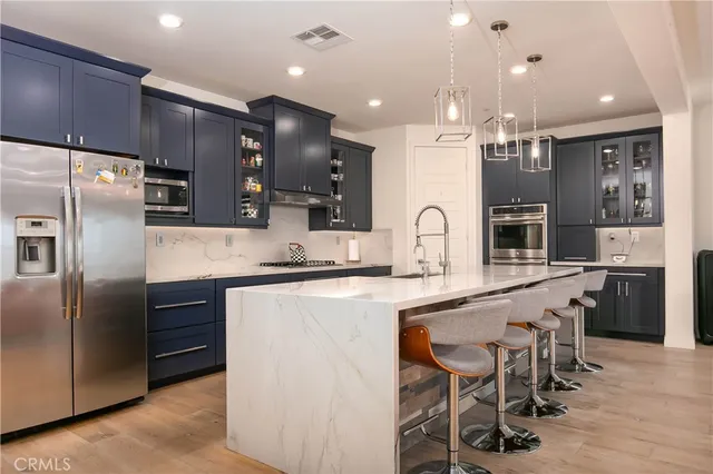 a large kitchen with cabinets chairs and refrigerator