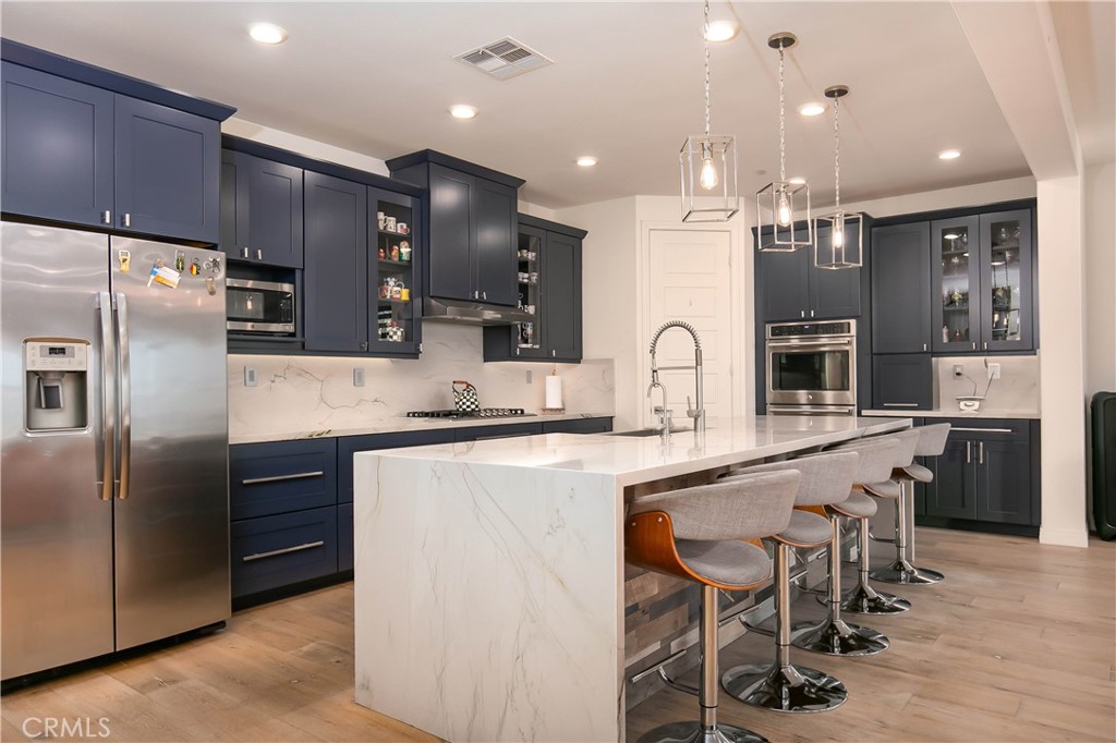 a large kitchen with cabinets chairs and refrigerator