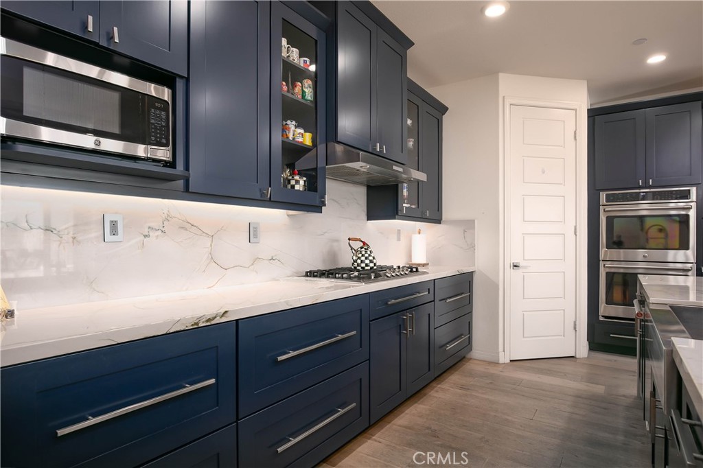 19680 Griffith Drive Saugus, CA 91350 - Photo 6 of 49 a kitchen with stainless steel appliances granite countertop a sink and a stove top oven with wooden floor