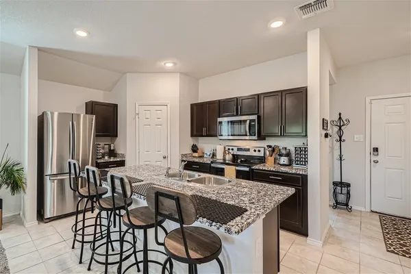 a kitchen with stainless steel appliances granite countertop a stove a refrigerator a sink a table and chairs
