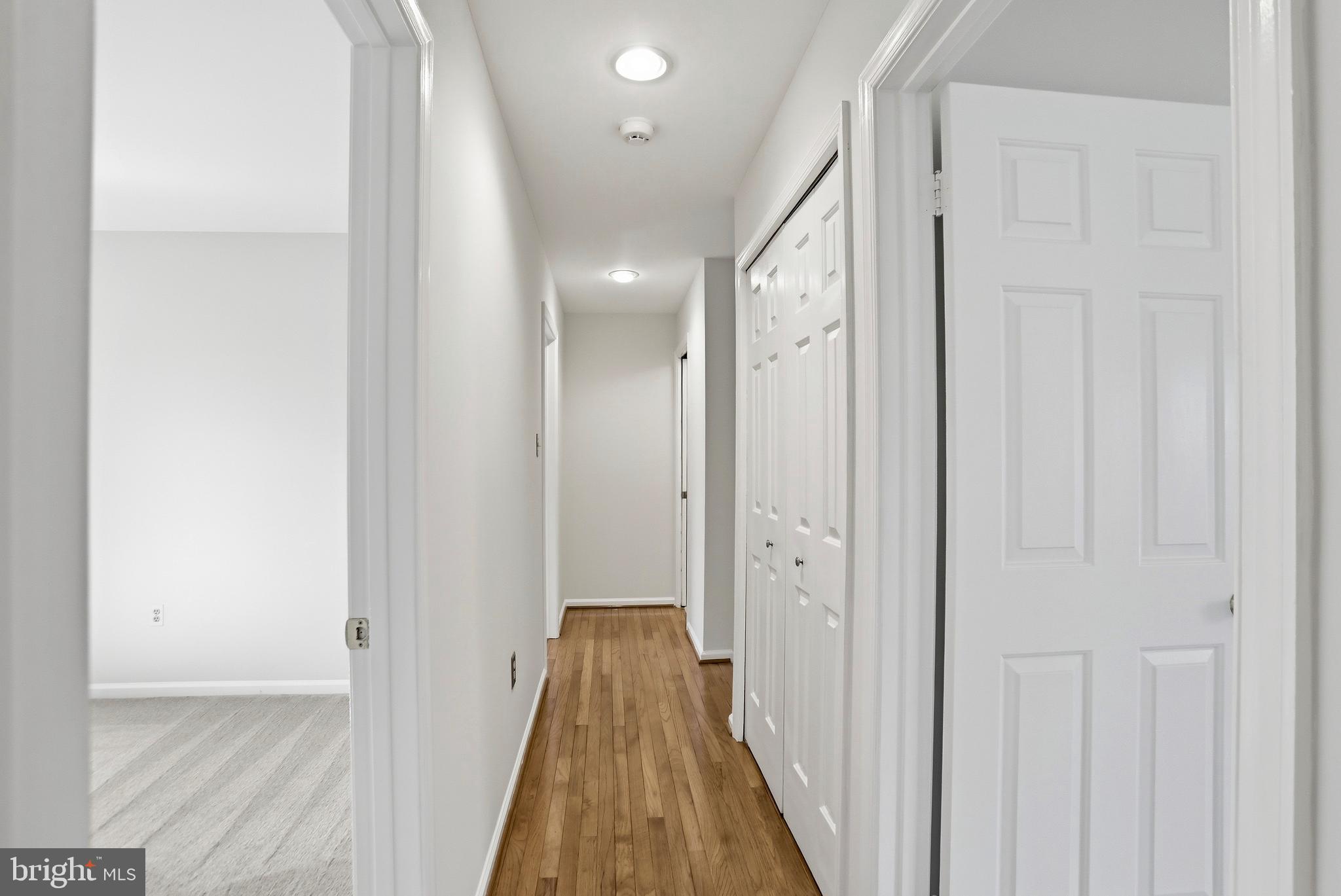 9202 Rockefeller Lane Springfield, VA 22153 - Photo 19 of 38 a view of a hallway with wooden floor and a bathroom