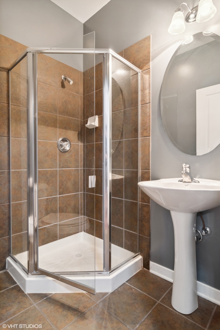 1244 West Monroe Street, Unit 7 Chicago, IL 60607 - Photo 16 of 18 a bathroom with a sink mirror and shower