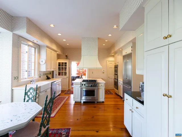 a large kitchen with sink a stove a dining table and chairs