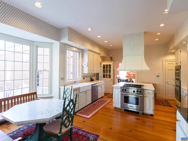 a kitchen with a stove a sink a refrigerator wooden floor and cabinets