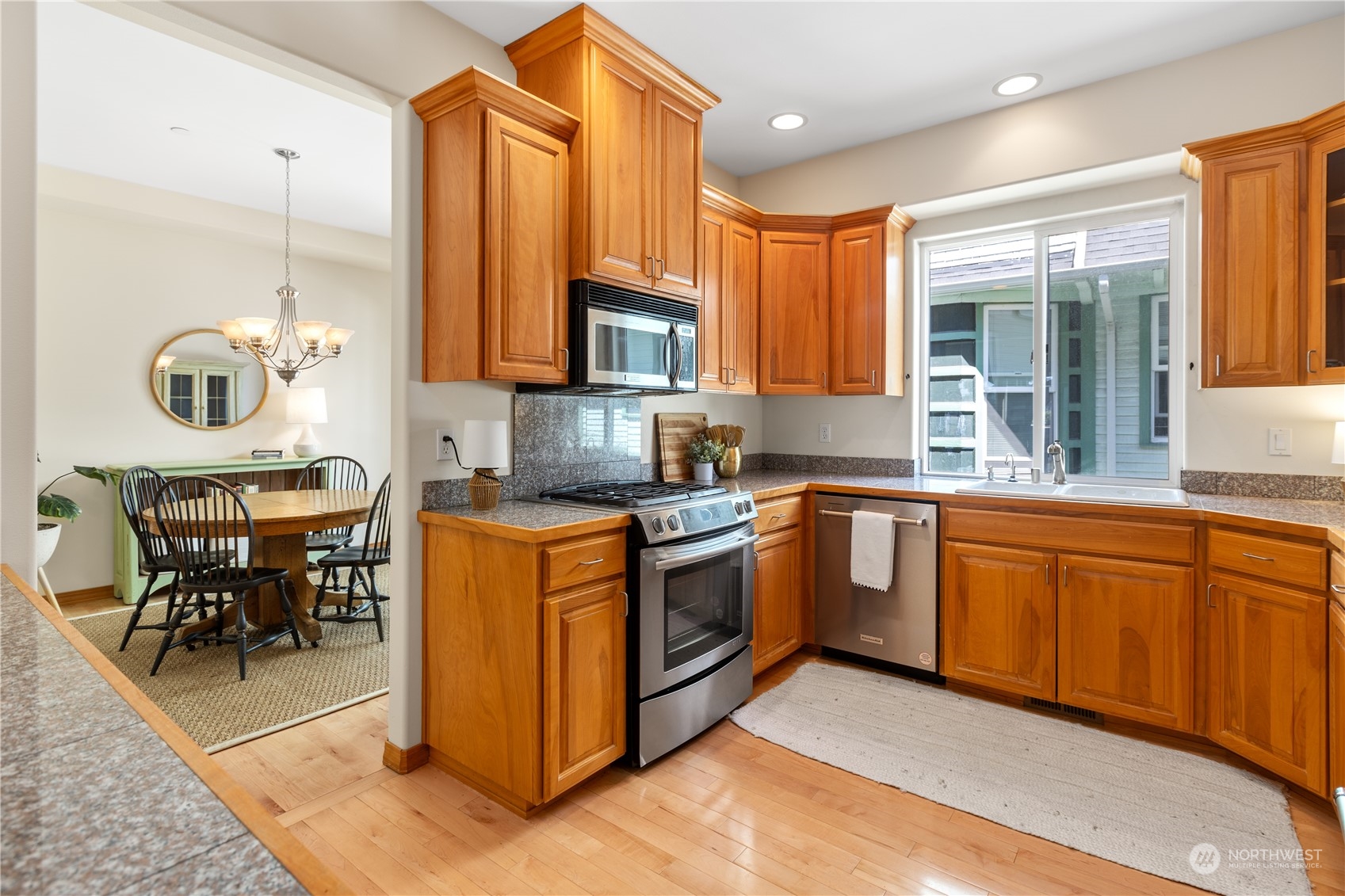 2030 Rucker Avenue, Unit 3 Everett, WA 98201 - Photo 12 of 40 a kitchen with stainless steel appliances granite countertop a stove top oven a sink dishwasher a dining table and chairs with wooden floor