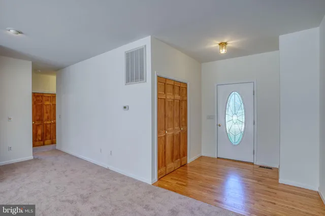 an empty room with mirror and wooden floor